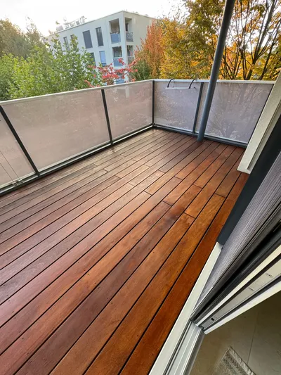 Frisch gepflegter Balkon in Winterthur mit geöltem Holzboden und Blick auf herbstliche Bäume – professionelle Holzbehandlung vom Malerbetrieb in Winterthur.
