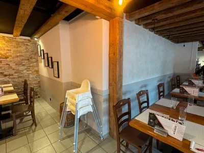 Edle Restaurantwand in Winterthur mit Stucco-Effekt und rustikalen Holzbalken – kombiniert mit Steinakzenten und warmem Licht, gestrichen vom Malerbetrieb in Winterthur.